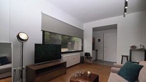 Un soggiorno moderno con una televisione a schermo piatto, una lampada da terra, un tavolino in legno e un divano.