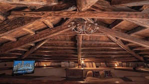 An attic room with exposed wooden beams, a chandelier, a television, bookshelves, and a cozy seating area. - The 1813 Painter s House by Neuvel (Delphi)