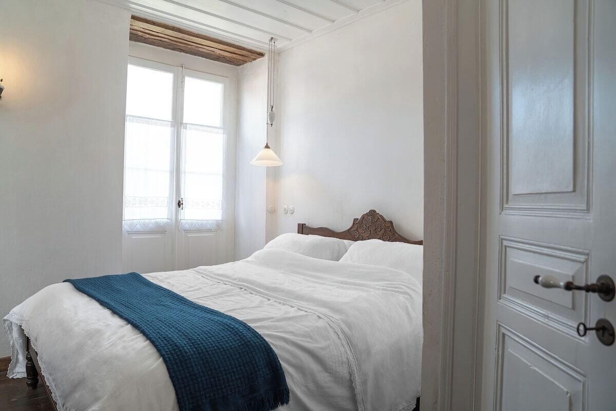 A bedroom with a bed, a window, and a door.