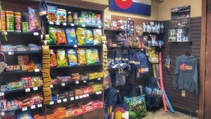 Negozio con scaffali pieni di snack, una bandiera del Colorado e diversi articoli in mostra.