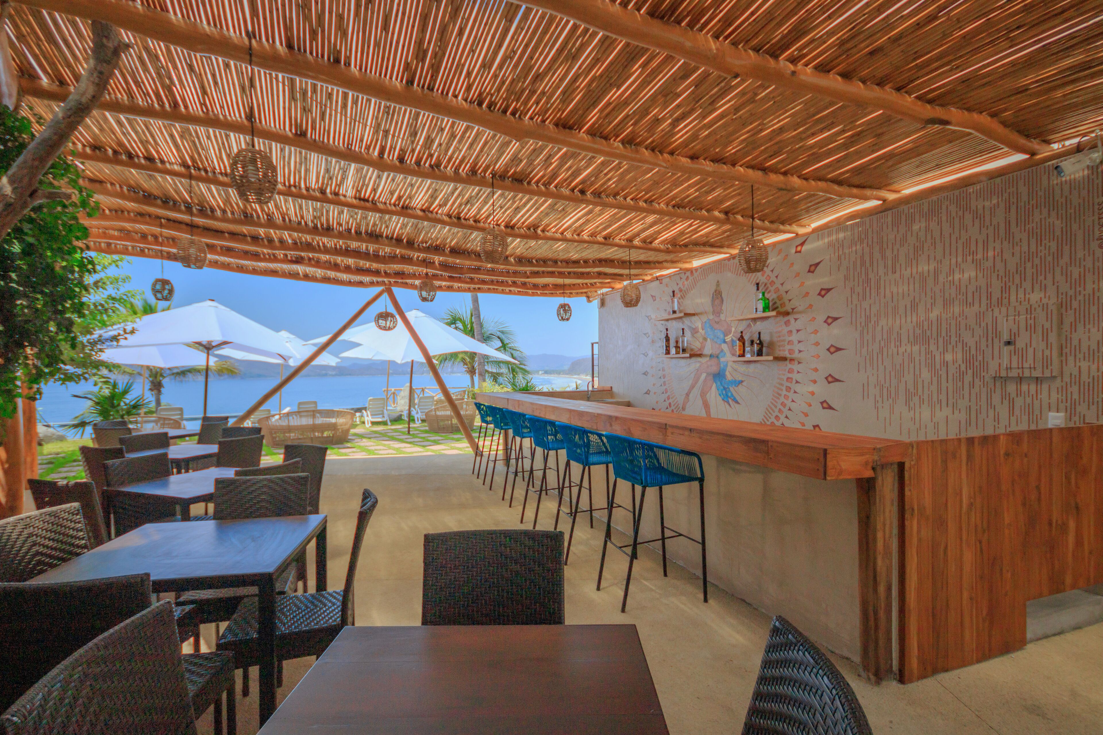 An outdoor dining area with a wooden bar and chairs, overlooking a scenic view.