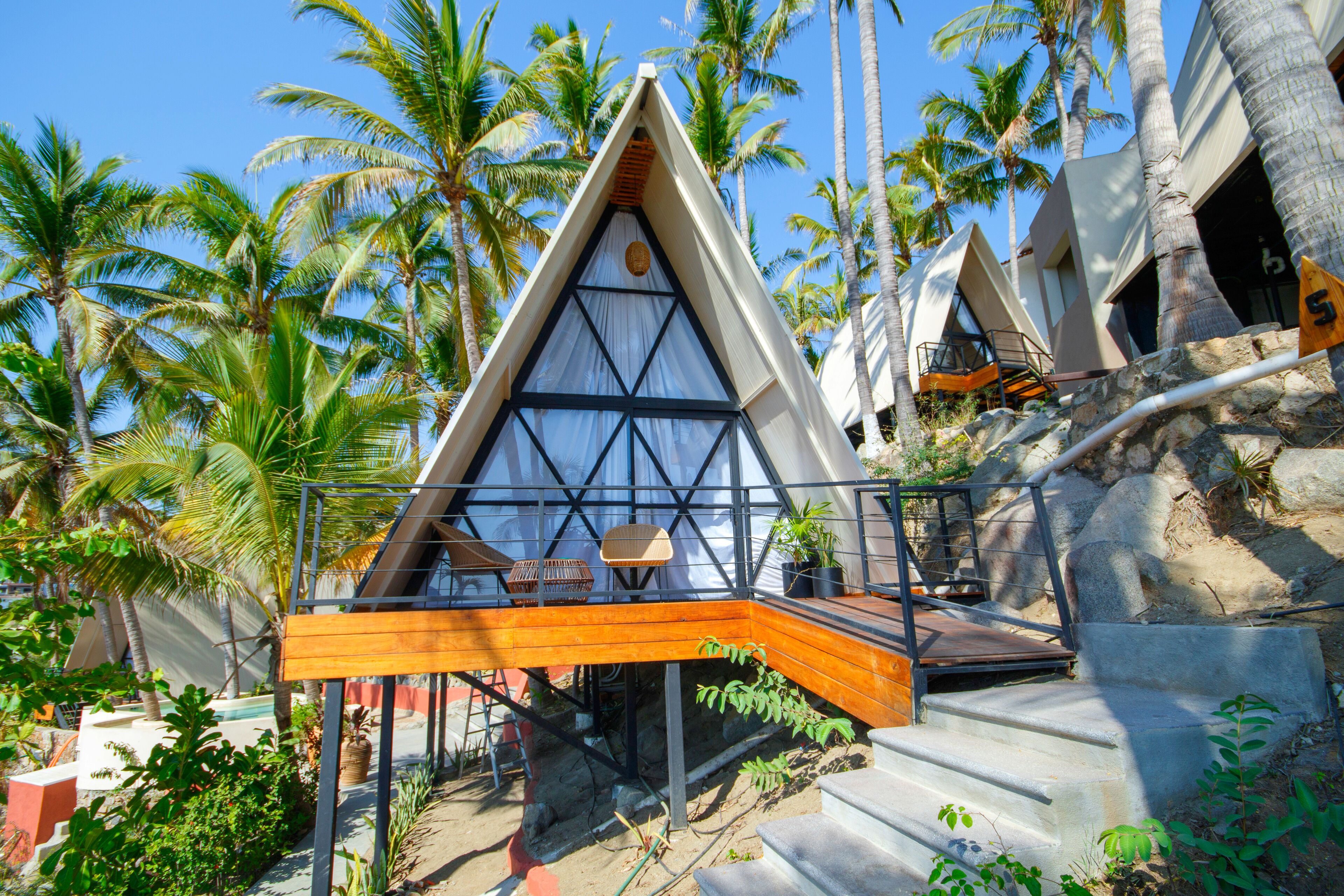 A modern, triangular-shaped building with a wooden deck and a staircase leading to a balcony.