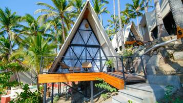 A modern, triangular-shaped building with a wooden deck and a staircase leading to a balcony.