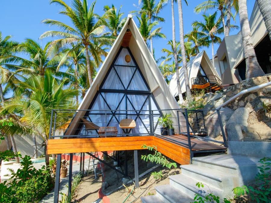 A modern, triangular-shaped building with a wooden deck and a staircase leading to a balcony.