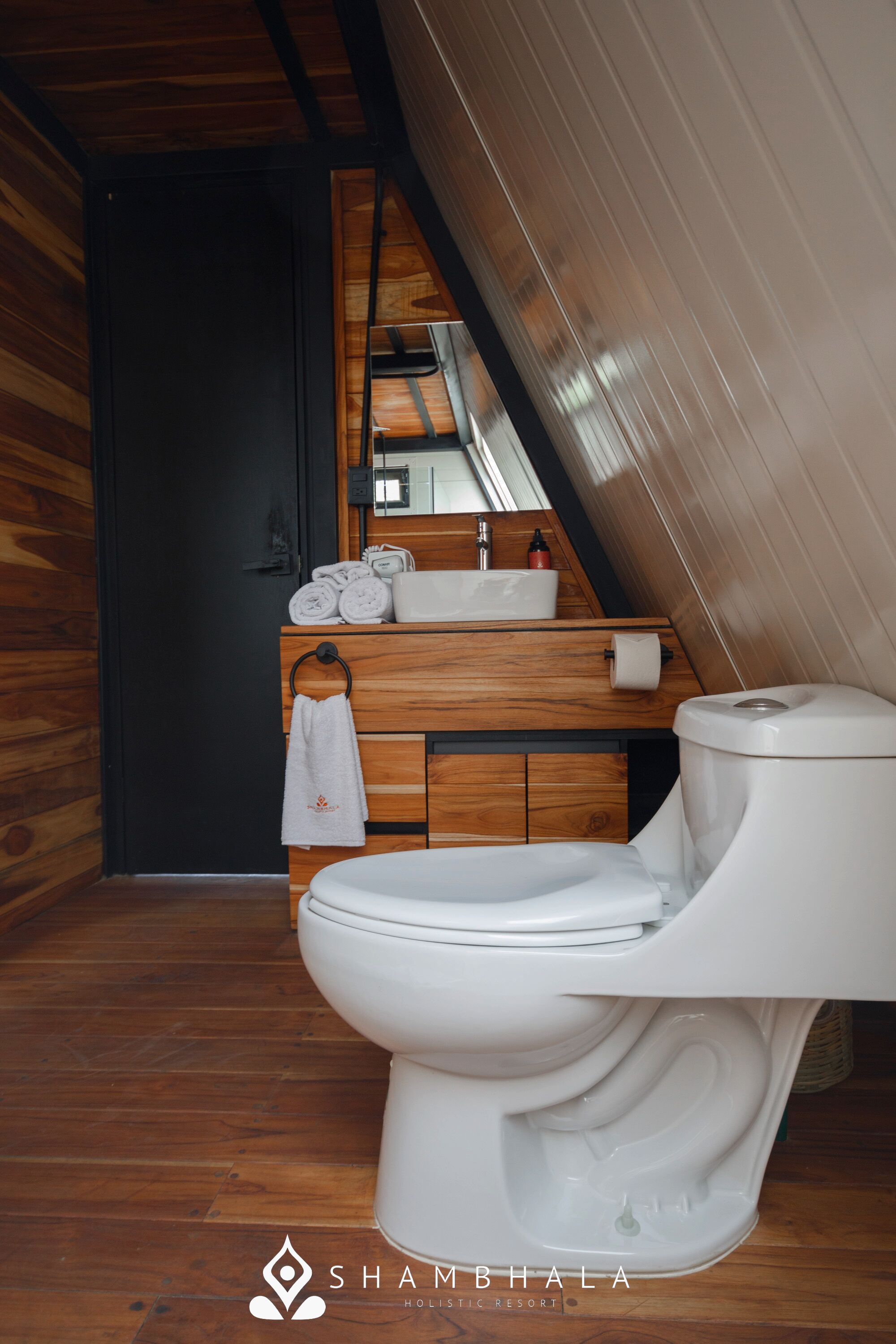 Un baño moderno con tocador de madera, inodoro y espejo.