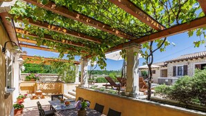 A covered outdoor patio with a table and chairs, stone walls, and a view of the surrounding landscape. - Villa Christina by Interhome (Tinjan)