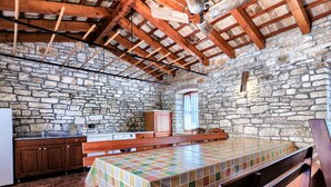 A rustic kitchen with stone walls, wooden beams, a wooden bench, and a tiled floor. - Villa Christina by Interhome (Tinjan)