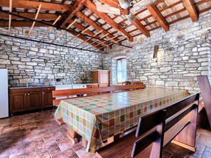 A rustic kitchen with stone walls, wooden beams, a wooden bench, and a tiled floor. - Villa Christina by Interhome (Tinjan)