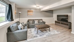 Una sala de estar moderna con un sofá gris, una mesa de centro y un mueble para la televisión.