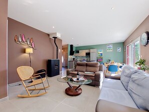 Ein modernes Wohnzimmer mit Sofa, Glastisch, Schaukelstuhl und Kamin.