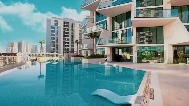 Un edificio moderno con piscina en la azotea, rodeado de rascacielos.