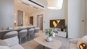 Una sala de estar moderna con comedor, una lámpara colgante blanca grande y un televisor montado en la pared.