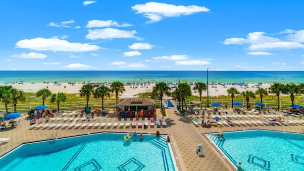 Een resort met twee zwembaden, een strand en een bar.