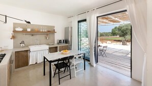 Une cuisine moderne avec un coin repas, de grandes portes-fenêtres coulissantes donnant sur une terrasse extérieure et une vue sur le paysage environnant.