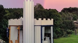 Un edificio moderno de una sola planta con techo plano, una columna vertical y un pequeño porche con dos sillas.