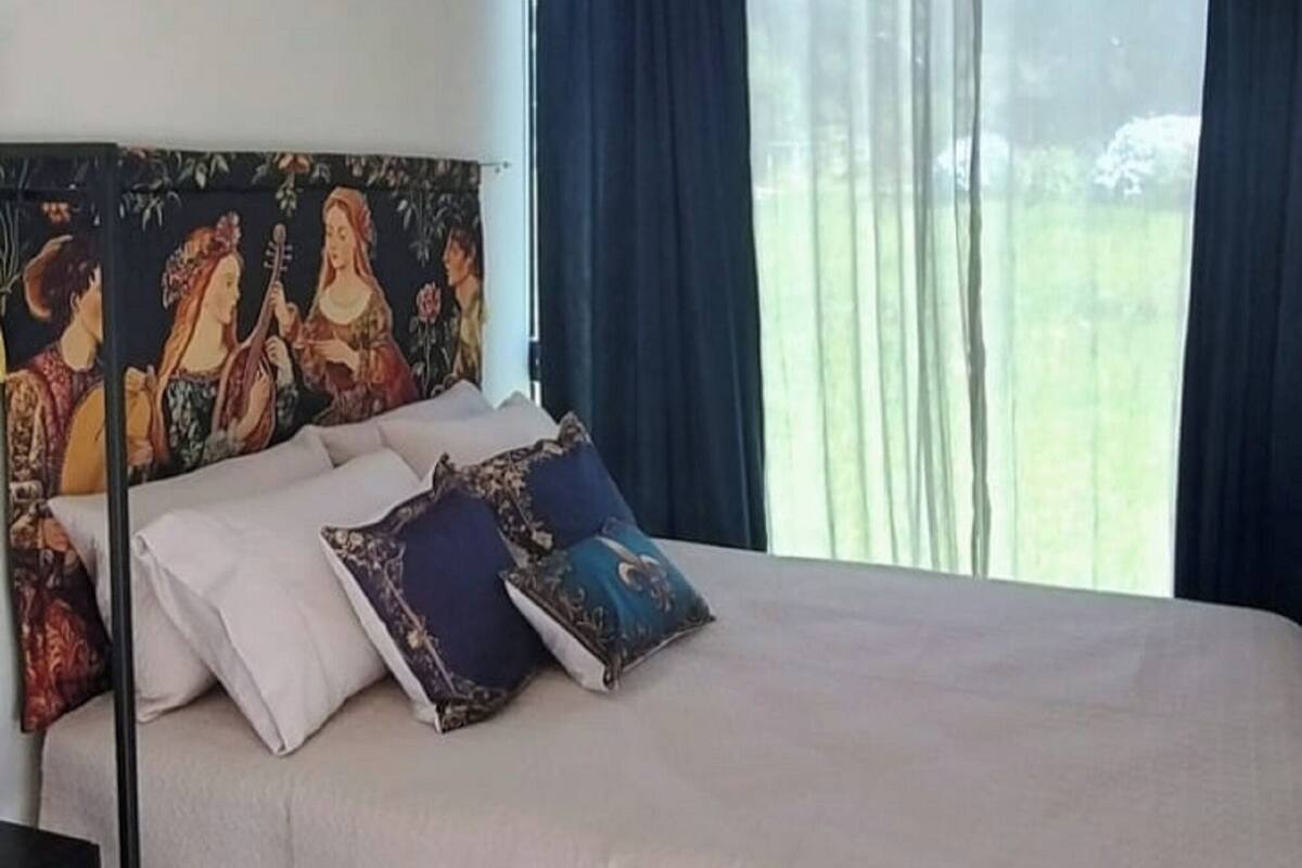 A single bed with a headboard, a bedside table, and a window with curtains.