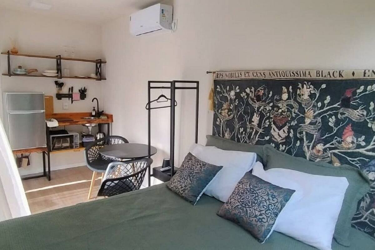 A bedroom with a bed, pillows, a desk, and a chair.