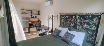 Un dormitorio con cama, almohadas, un escritorio y una silla.