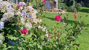 Un jardín con un pabellón, abundante follaje y plantas florecientes.