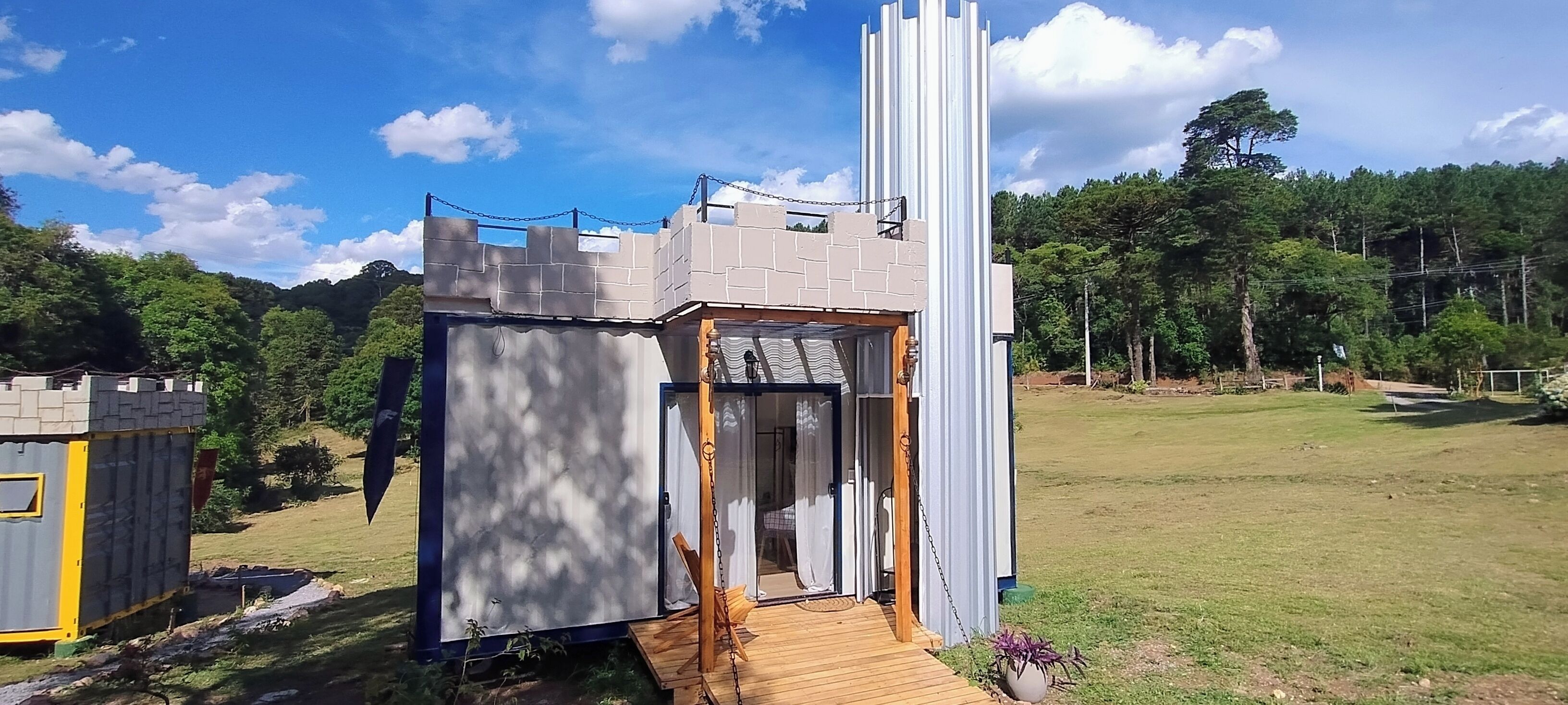 A small, castle-like structure with a wooden deck and a chain-link fence.