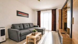 Een moderne woonkamer met een grijze bank, een houten salontafel en een tv-meubel.