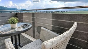 Een balkon met een tafel, stoelen, een bloempot en een boek.