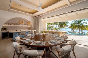 A round dining table set for six with a view of the ocean and palm trees. - La Coleccion (Isla Mujeres)
