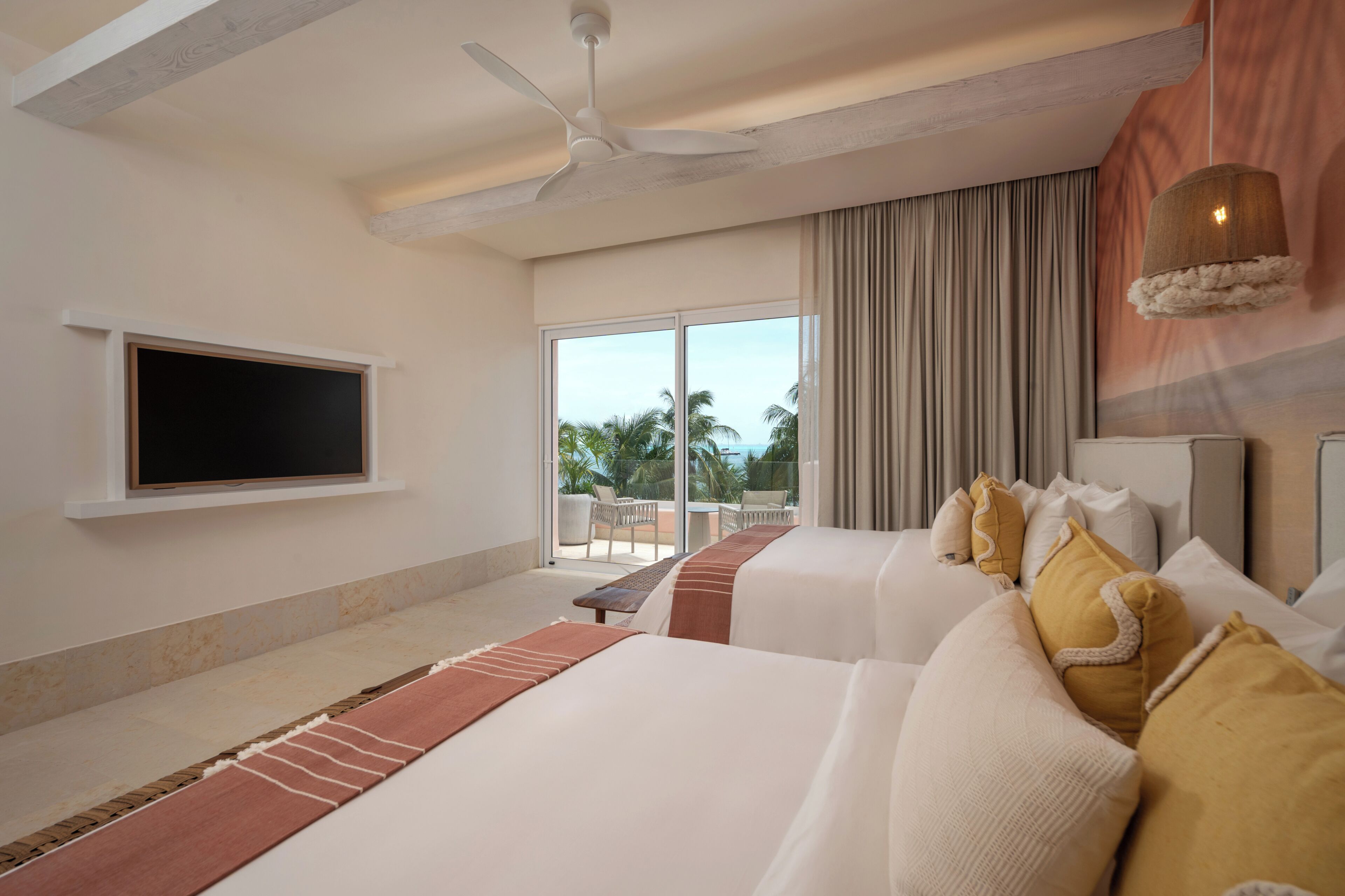 Una camera d'albergo con un letto, una televisione, una ventola a soffitto e vista sull'esterno.