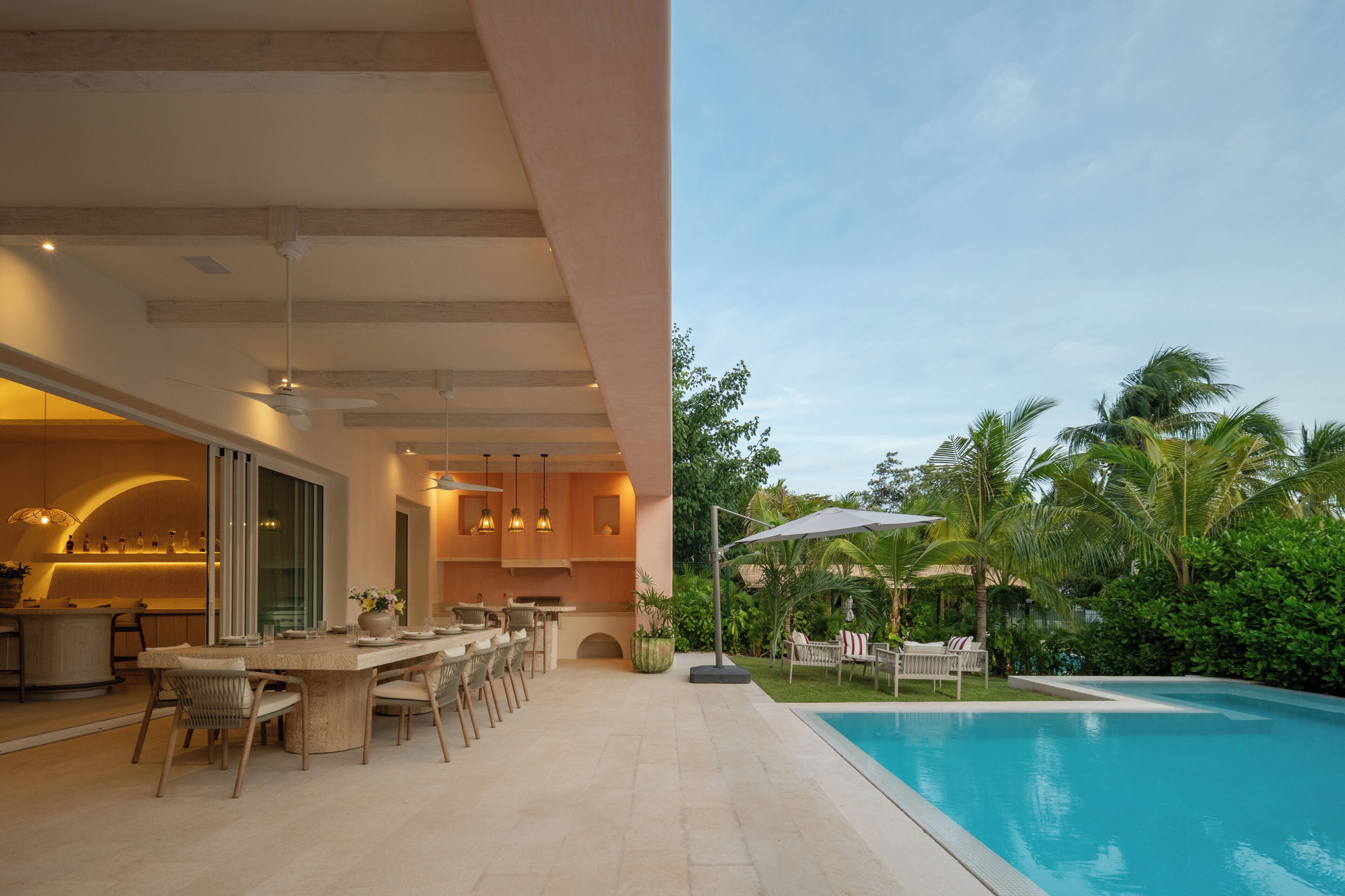 Un área moderna de cocina al aire libre con un comedor y una zona de descanso junto a la piscina.