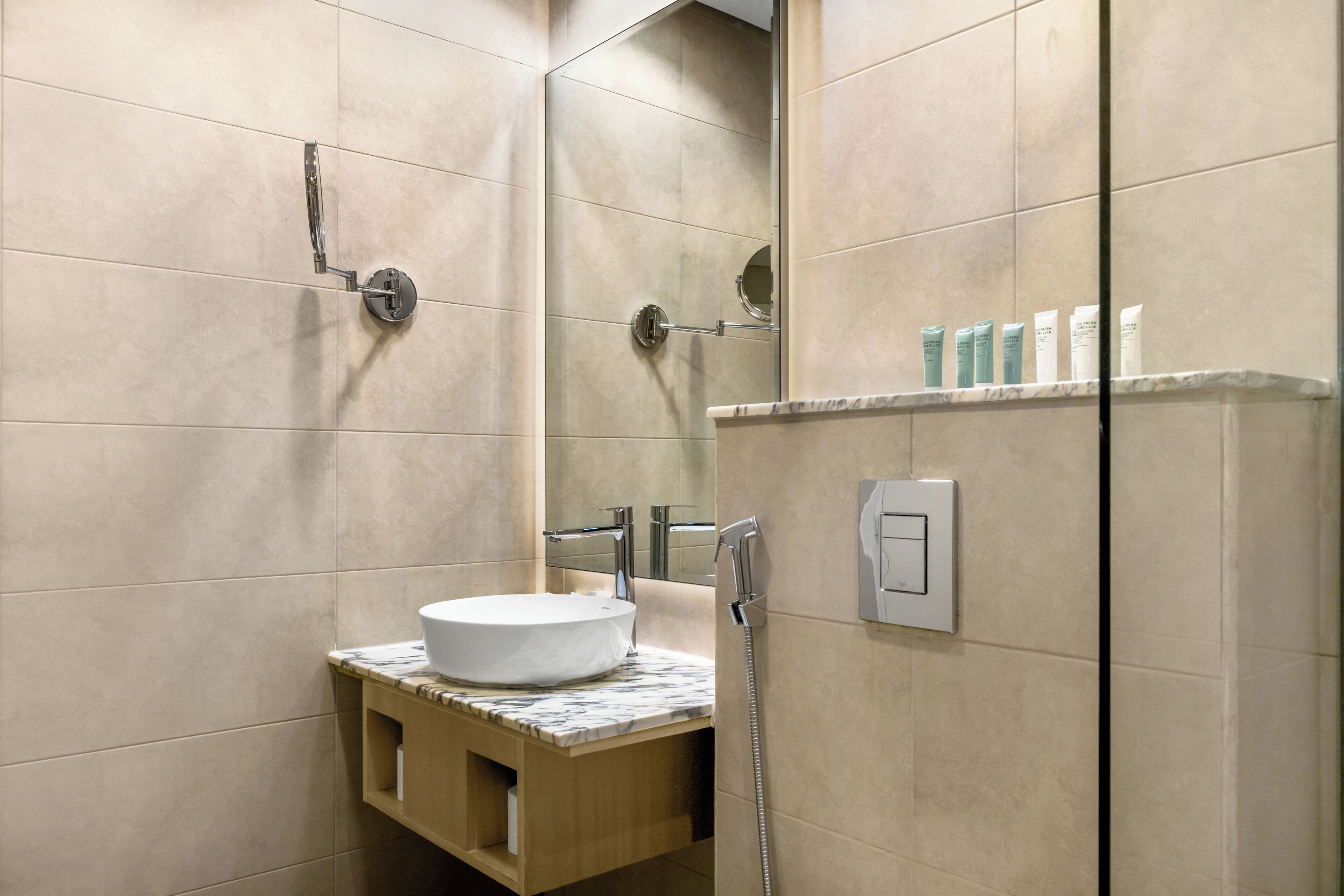 A modern bathroom with a marble sink, a handheld showerhead, and a mirror.