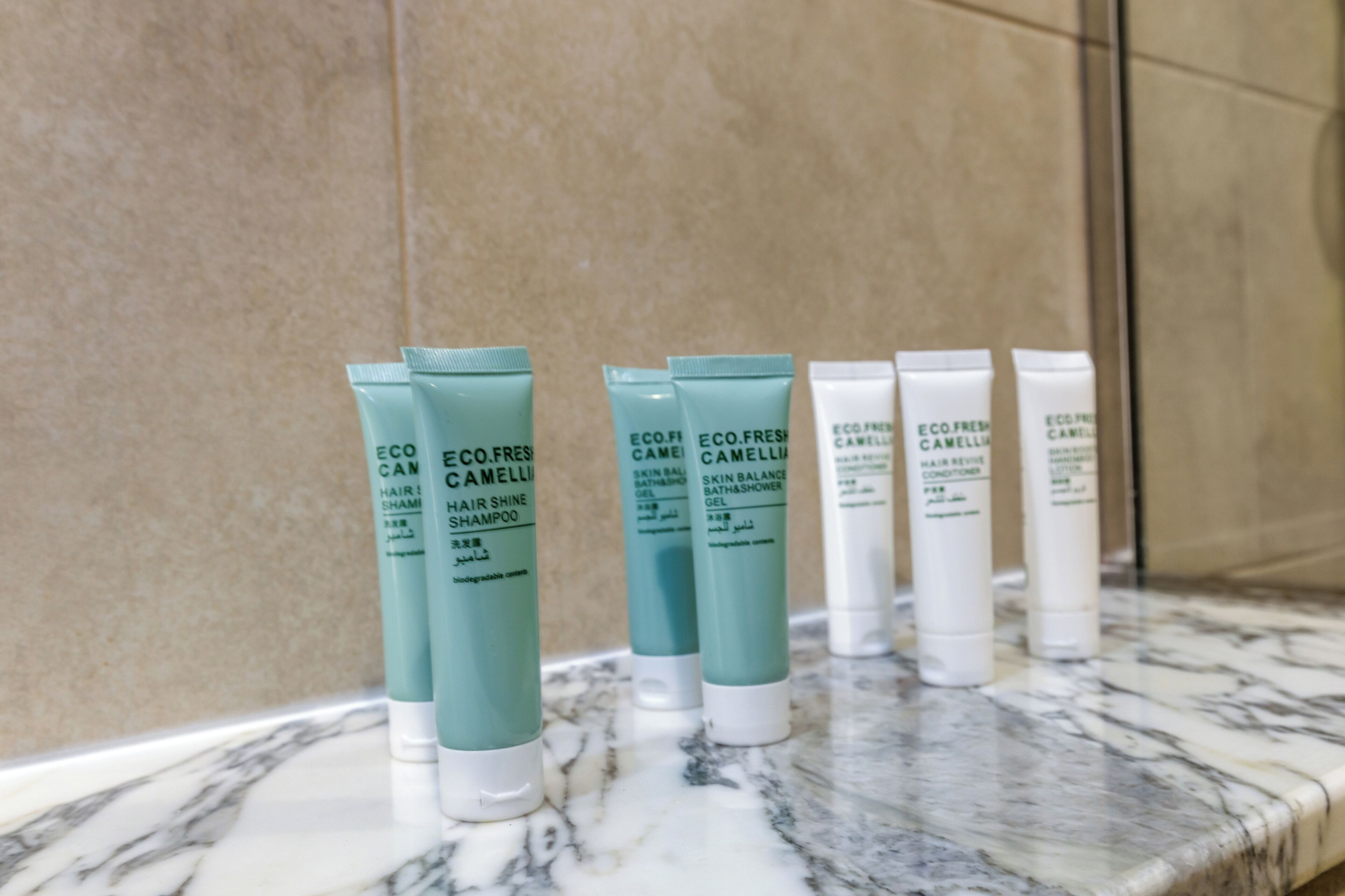 A bathroom with a marble countertop displaying various hair care products.