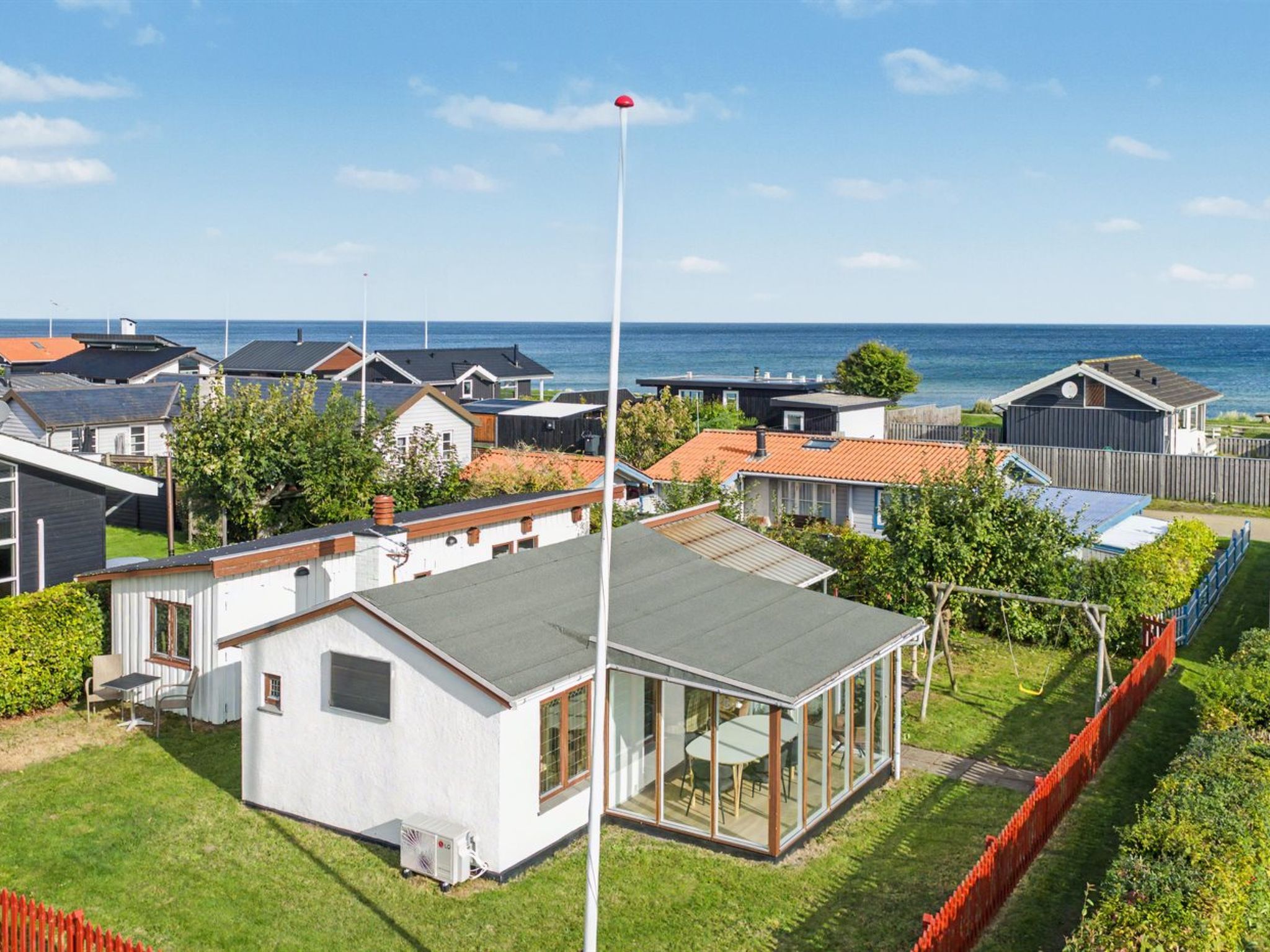 Ett bostadsområde med hus, en flaggstång och utsikt över havet.