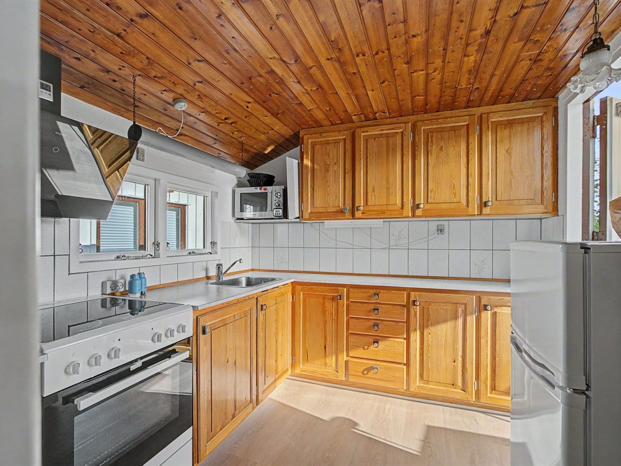 A kitchen with wooden cabinets, a microwave, a sink, and a stove.