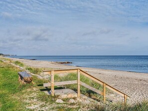 Une plage avec une structure en bois, peut-être une promenade, qui mène à l’eau.