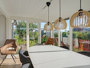 Un espace de salle à manger moderne avec une table blanche, des chaises noires et marron, et des luminaires suspendus au design sphérique.