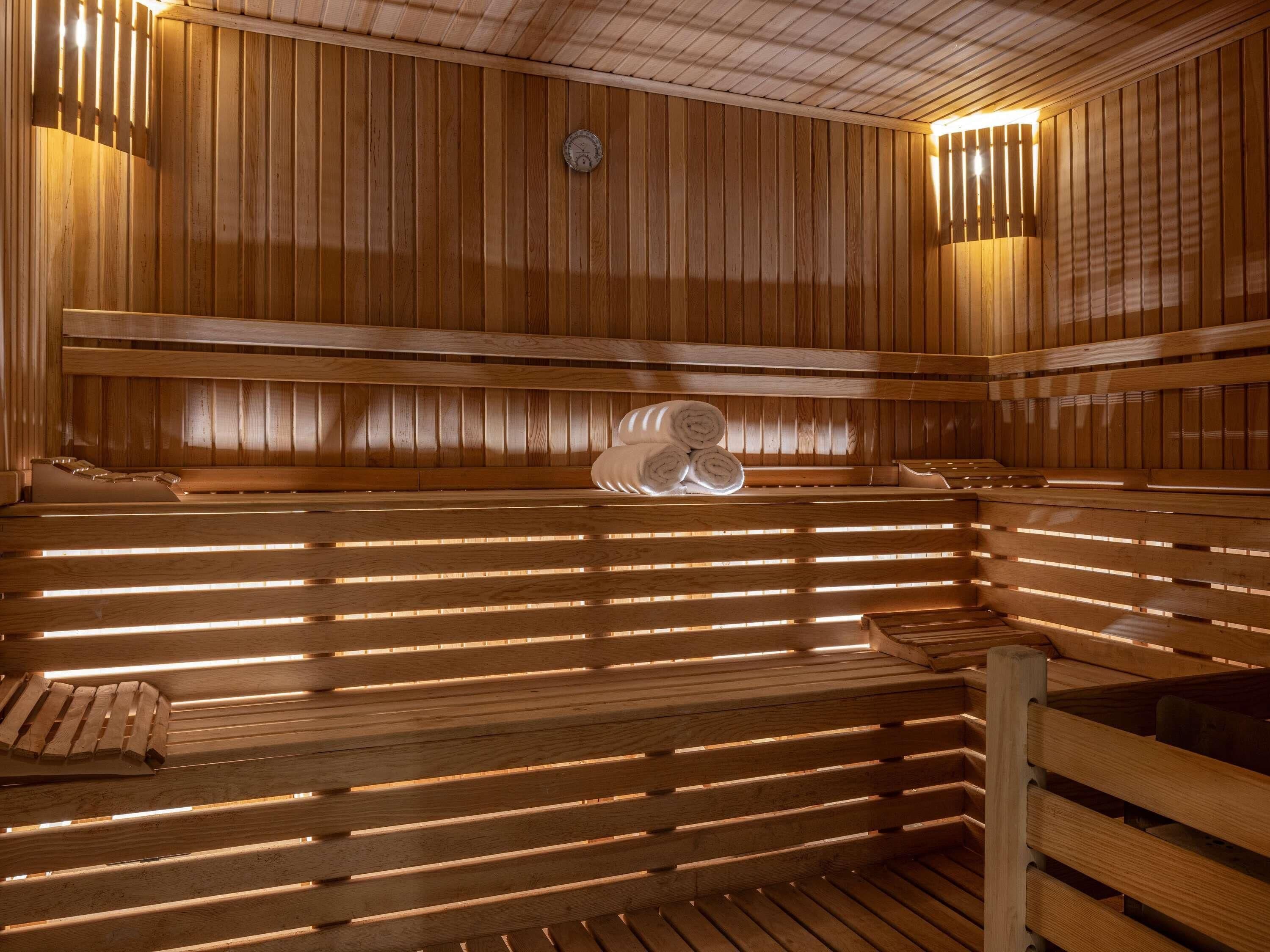 Un sauna avec des bancs en bois, une horloge et un porte-serviettes.