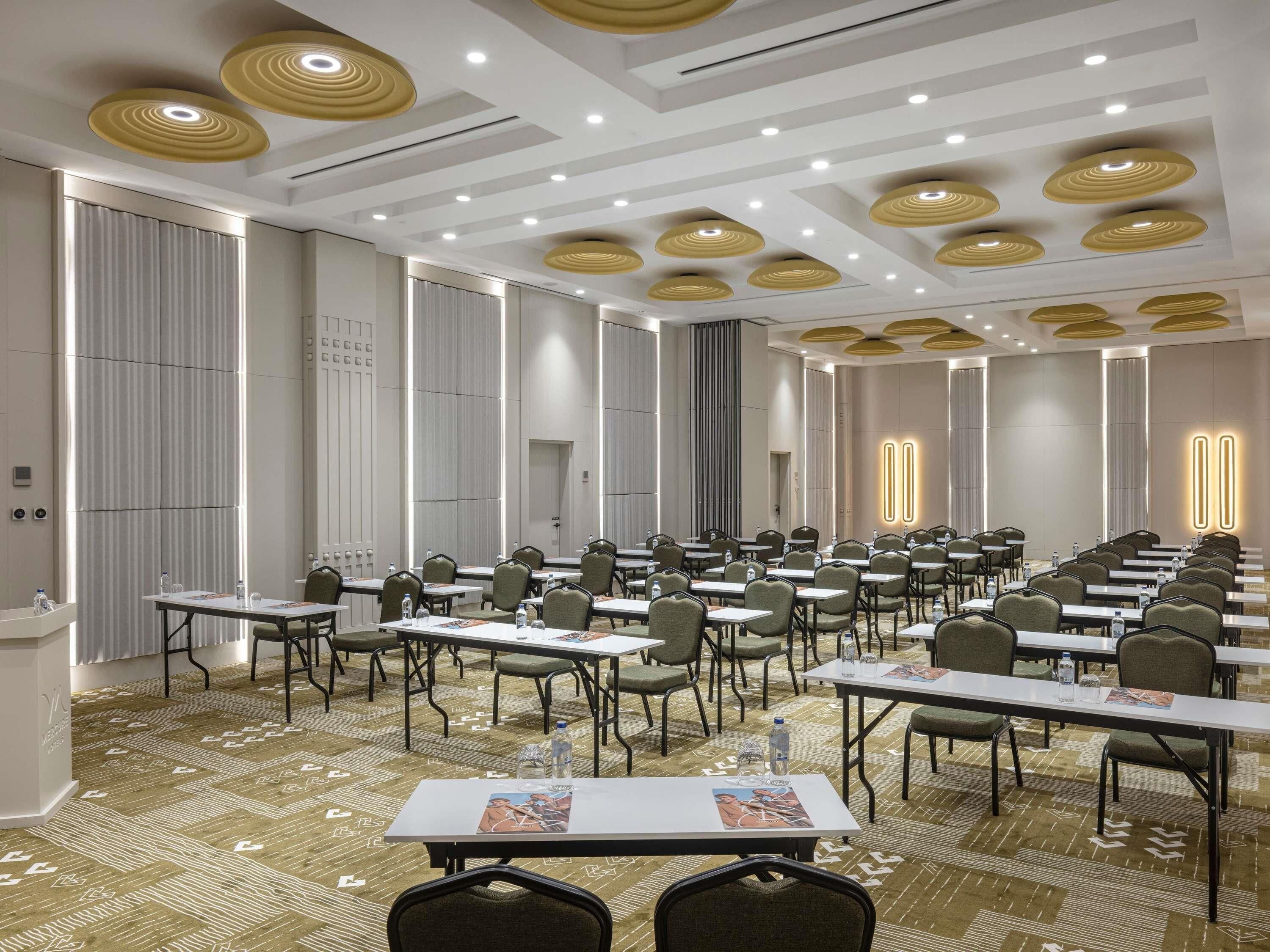 Une salle de conférence équipée de tables, de chaises et d’un tapis à motifs.