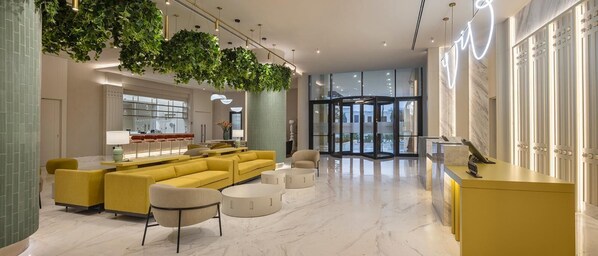 A modern lobby with a yellow sofa set, a reception desk, and a glass entrance. - Mercure Antalya Belek (Serik)