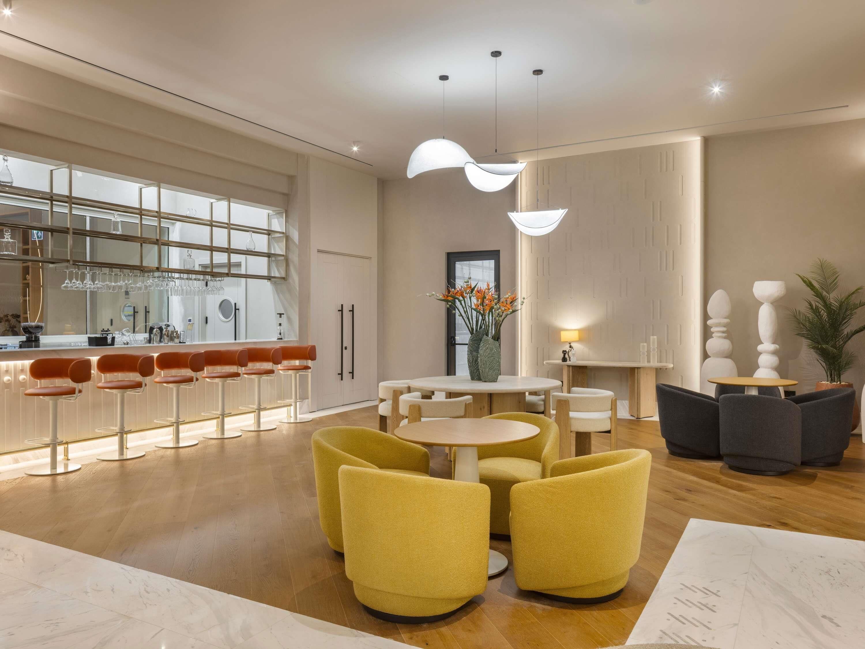 Un hall d’hôtel moderne avec un bar, des espaces aménagés pour s’asseoir et une plante décorative.
