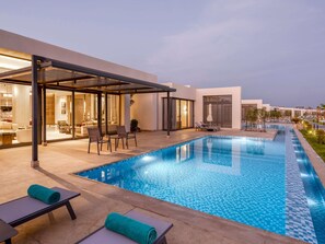 A modern outdoor pool area with lounge chairs and a covered seating area.