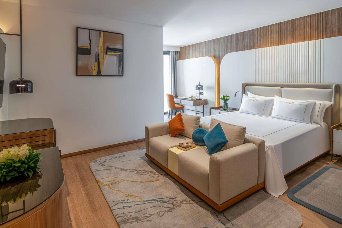 Une chambre d’hôtel moderne équipée d’un lit, d’un canapé, d’un bureau et d’un miroir.