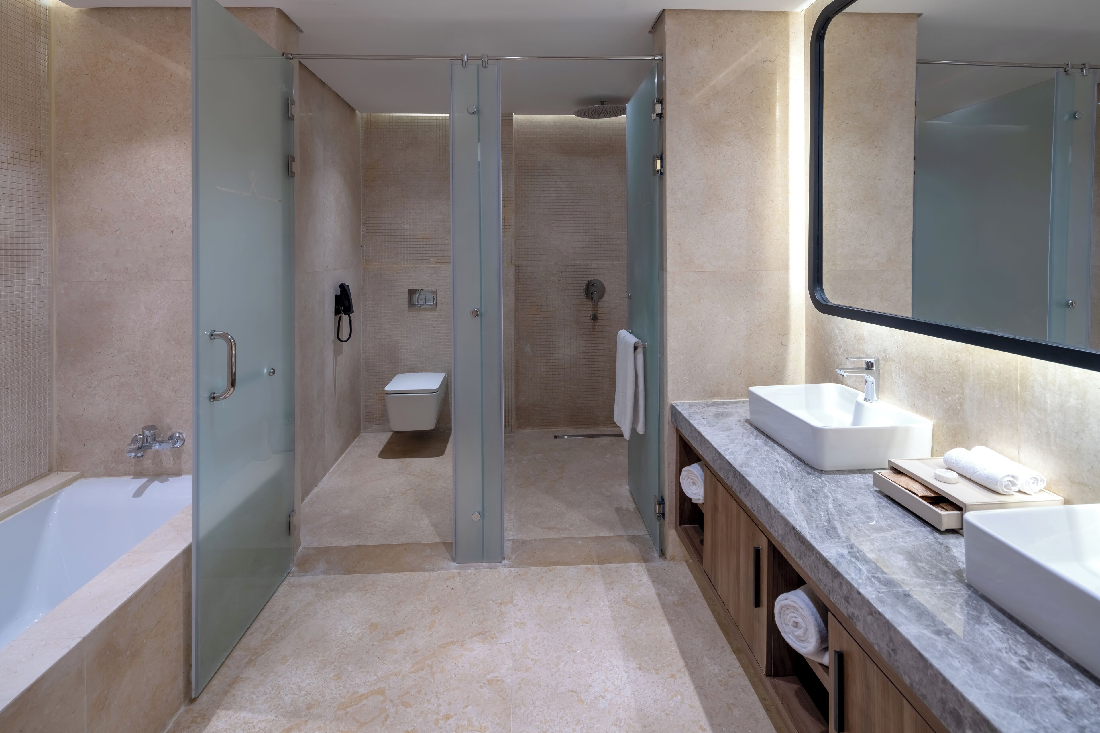 A modern bathroom with a glass-enclosed shower, a bathtub, a toilet, and a vanity with a sink and mirror.