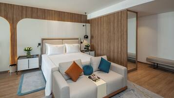 Un dormitorio moderno con cama, sofá, mesita de noche y espejo.