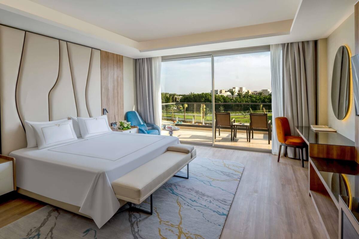 Une chambre d’hôtel moderne dotée d’un grand lit, d’un bureau et d’un balcon avec vue.