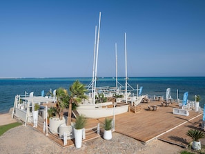 Un port de plaisance avec des bateaux, des espaces de détente en plein air et une vue dégagée sur la mer.