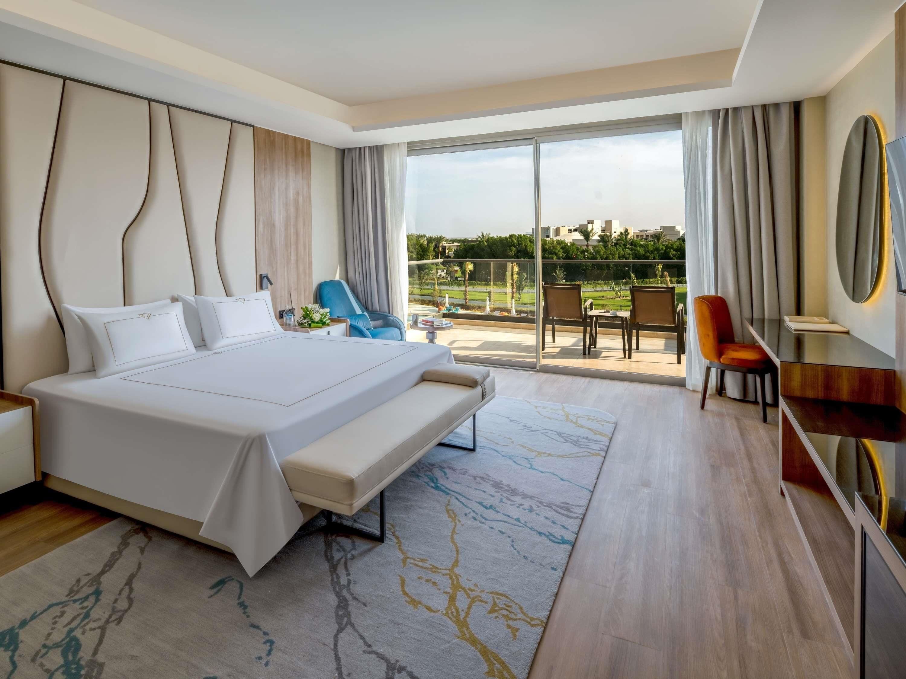 Habitación de hotel moderna con una cama grande, un escritorio y un balcón con vistas.
