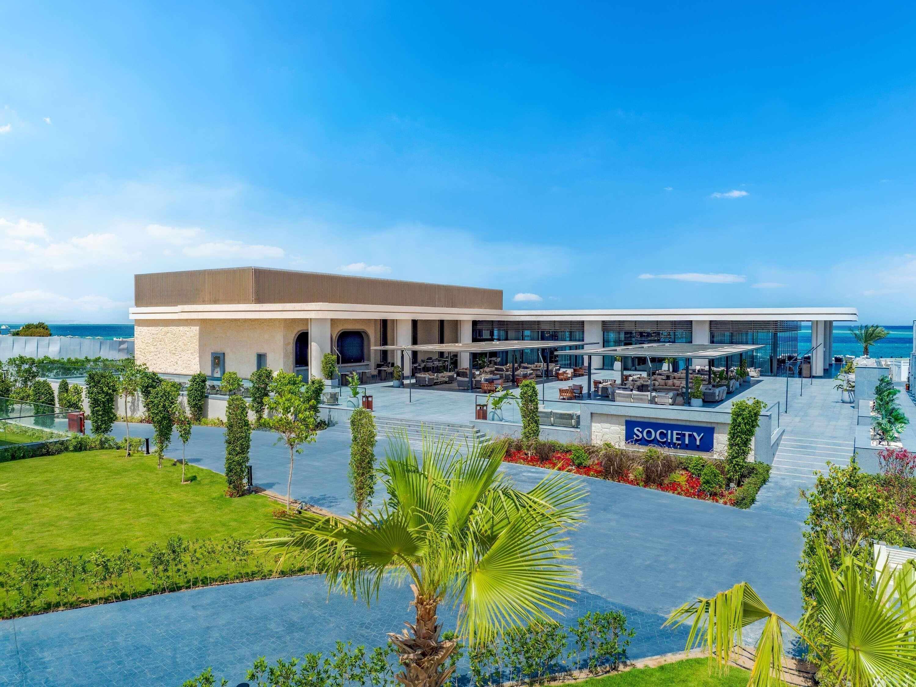 A modern building with a covered outdoor seating area and a pool.