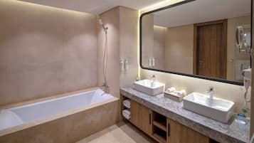 A modern bathroom with a bathtub, two sinks, a large mirror, and a shower.