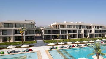 Un hotel moderno con area piscina, diversi balconi e cielo sereno.