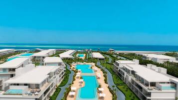 Un resort con múltiples piscinas, una piscina central y vistas al océano.